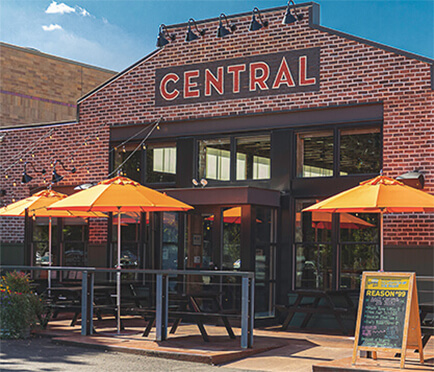 Several orange Frankford Market Umbrellas being used in front of a restaurant