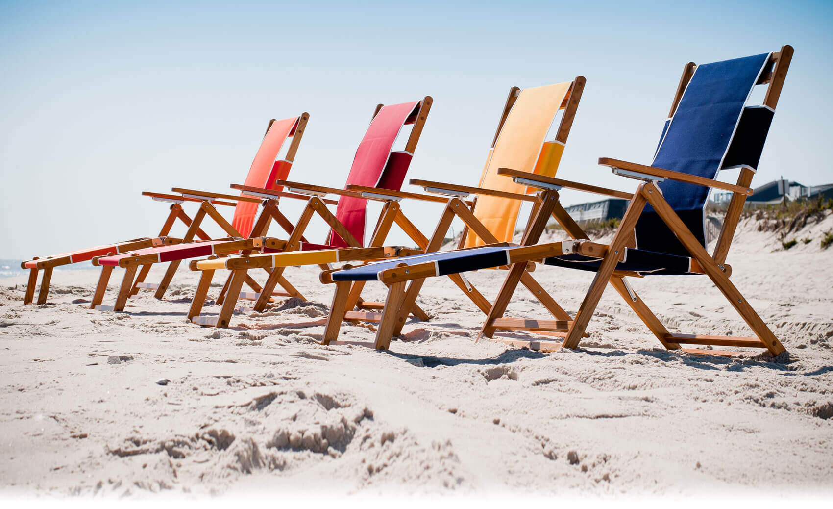 Four Frankford Beach Oakwood Loungers set up on the beach sand