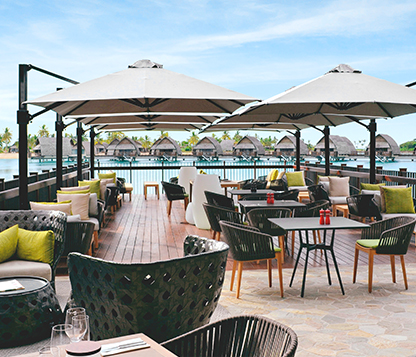 Several white Frankford Eclipse Cantilever Umbrellas shade a dining area by the water at a resort in Fiji