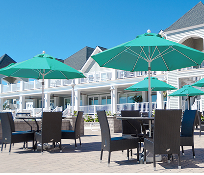 Several turquoise Octagon Frankford Monterey Pulley Lift Umbrellas shading tables at a beach club in New Jersey