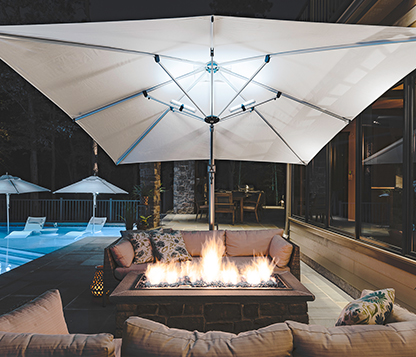 A white Frankford Square Eclipse Cantilever Umbrella shades a backyard firepit by a pool at night in Medford, NJ