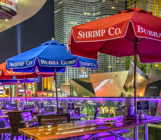 Red and blue Frankford Patio Umbrellas with Bubba Gump Shrimp branding designs set up at an evening dining location
