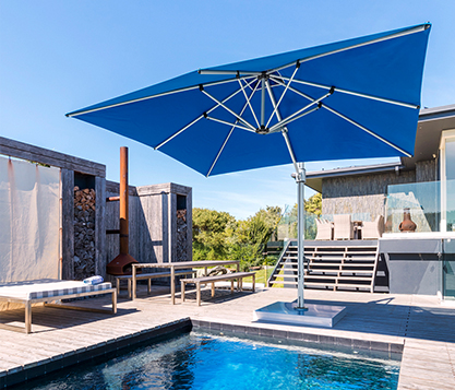 A blue Frankford Square Aurora Cantilever Umbrella provides shade over a backyard pool in Auckland, New Zealand