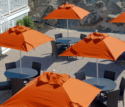 Orange Frankford Market Umbrellas set up over tables at a large property